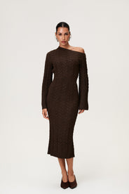 Woman wearing the Arona knitted midi dress in brown melange with one padded shoulder, full-length sleeves, a back slit, and a heavy cable-knit design. thumbnail image