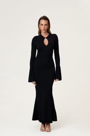 Woman wearing the knitted Basel maxi dress in black, featuring a cutout design at chest area and long, flared sleeves. thumbnail image