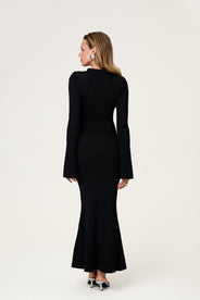 Woman wearing the knitted Basel maxi dress in black, featuring a cutout design at chest area and long, flared sleeves. thumbnail image