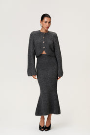 Woman wearing a Cessole midi skirt and Cessole cardigan in dark grey. The skirt features a structured knit, midi length, zipper on the side, curved cutline in the waist, and softly flared bottom. thumbnail image