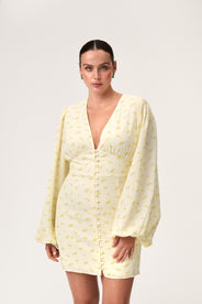 A model wearing a pastel yellow mini dress with wide balloon sleeves, a V-shaped neckline, and buttons along the front. The dress has a hidden zipper in the back and is fully lined. thumbnail image