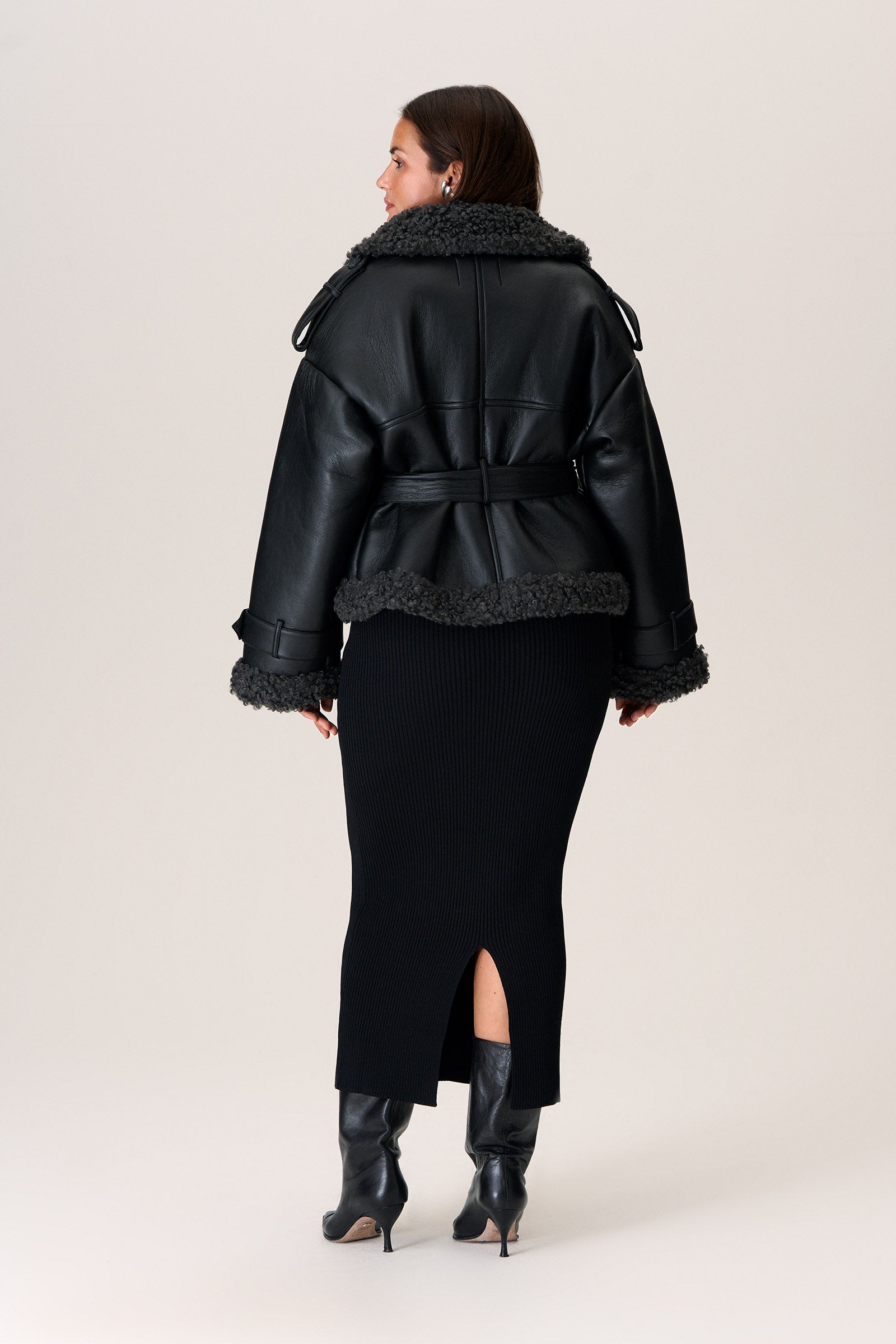 A model wearing a black Manchester cropped jacket with oversized fit, faux shearling lining, side pockets, and a belt with a D-shaped buckle. image