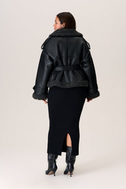A model wearing a black Manchester cropped jacket with oversized fit, faux shearling lining, side pockets, and a belt with a D-shaped buckle. thumbnail image