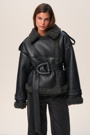 A model wearing a black Manchester cropped jacket with oversized fit, faux shearling lining, side pockets, and a belt with a D-shaped buckle. thumbnail image