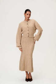 Woman wearing the Merano maxi dress in beige melange with the Merano cardigan in beige melange, a sleek, figure-flattering style with delicate singlet straps, a deep V-neckline, and an hourglass fit. thumbnail image
