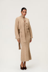 Woman wearing the Merano scarf in beige melange, styled with Merano dress and Merano cardigan in beige melange. The scarf is a lightweight knit with a soft texture, perfect for year-round layering. thumbnail image