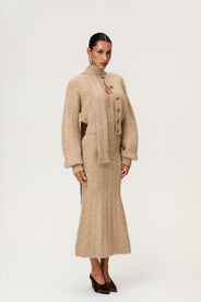 Woman wearing the Merano scarf and Merano cardigan styled with the Merano maxi dress in beige melange, a sleek, figure-flattering style with delicate singlet straps, a deep V-neckline, and an hourglass fit. thumbnail image