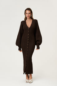 Woman wearing the Montana maxi dress in brown melange featuring an hourglass knit with a button-up front, V-neck collar, and balloon sleeves with cuff details. thumbnail image