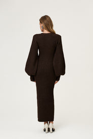 Woman wearing the Montana maxi dress in brown melange featuring an hourglass knit with a button-up front, V-neck collar, and balloon sleeves with cuff details. thumbnail image