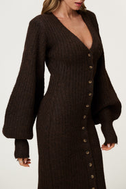 Woman wearing the Montana maxi dress in brown melange featuring an hourglass knit with a button-up front, V-neck collar, and balloon sleeves with cuff details. thumbnail image