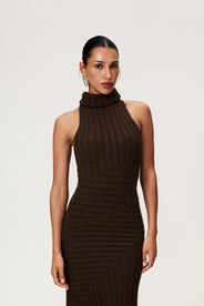 Woman wearing the Montreux maxi dress in brown melange with a voluminous halterneck, light wool-blend knit, and asymmetric panel details that flatter the figure. thumbnail image