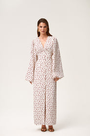 A model wearing Positano dress, size 34, a red cherry print maxi dress with long sleeves, a V-neck collar, and front slits. thumbnail image