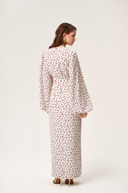 A model wearing Positano dress, size 34, a red cherry print maxi dress with long sleeves, a V-neck collar, and front slits. thumbnail image