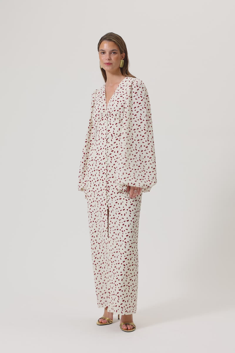 A model wearing Positano dress, size 34, a red cherry print maxi dress with long sleeves, a V-neck collar, and front slits.